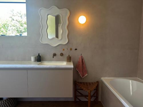 a bathroom with a sink and a tub and a mirror at The Driving Creek Cottage in Coromandel Town