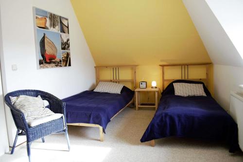ダゲビュルにあるNiels Husのベッド2台と椅子1脚が備わる屋根裏部屋です。