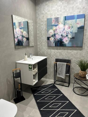 a bathroom with a sink and a painting of flowers at Villa Sol e Mar in Ribeira Brava