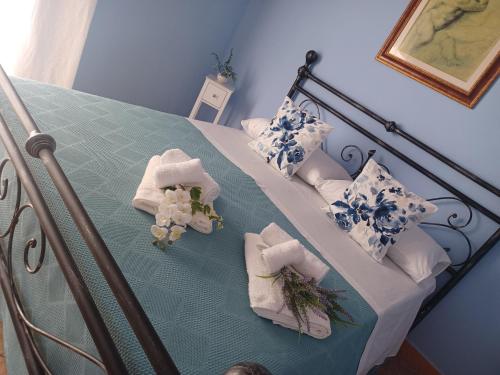 a bed with blue and white pillows and towels at Casa Vacanza Io e Te in San Marco Argentano