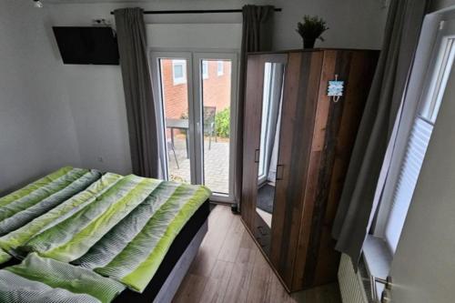 une chambre avec un lit et une porte coulissante en verre dans l'établissement Ferienwohnung Wildgans 2 Dollart Ostfriesland, à Bunde