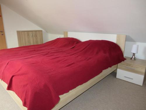 a bed with a red blanket on top of it at Neu Haus Koralle an der Nordsee in Dornumergrode
