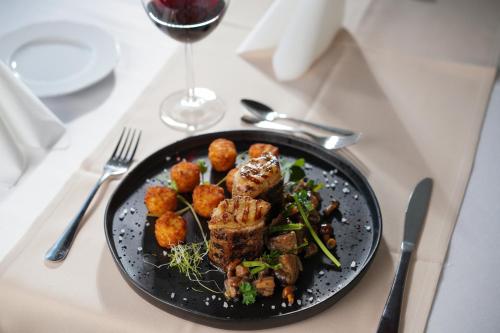 a plate of food on a table with a glass of wine at Szalajka Fogadó és Étterem in Szilvásvárad