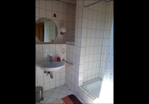 a white tiled bathroom with a sink and a tub at NEU! Ferienwohnung Luna zwischen den Meeren in Ihlow