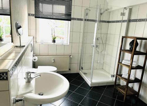 uma casa de banho branca com um lavatório e um chuveiro em Modernes Ferienhaus Sauerblick em Langsur