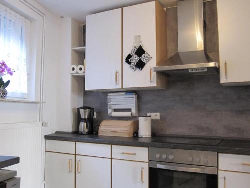 a kitchen with white cabinets and a stove top oven at Ferienhaus am Rheinsteig in Kaub