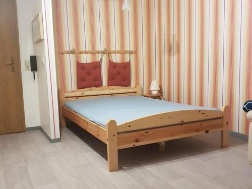 Cama de madera en una habitación con pared de rayas en NEU! Fewo Küstenstube en Schweiburg