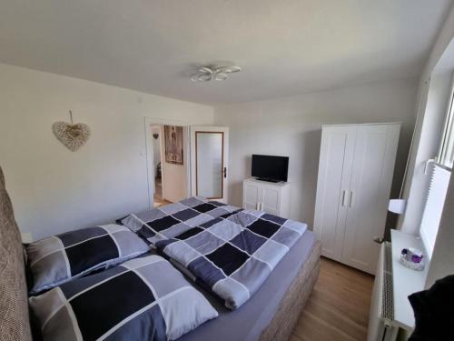 a bedroom with a black and white bed and a television at Ferienhaus Am Zollhaus in Teplingen
