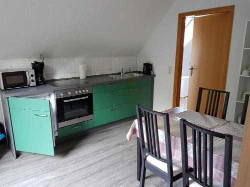 a kitchen with green cabinets and a sink and a table at NEU Ferienwohnung Kropp OG - Rechts in Kropp