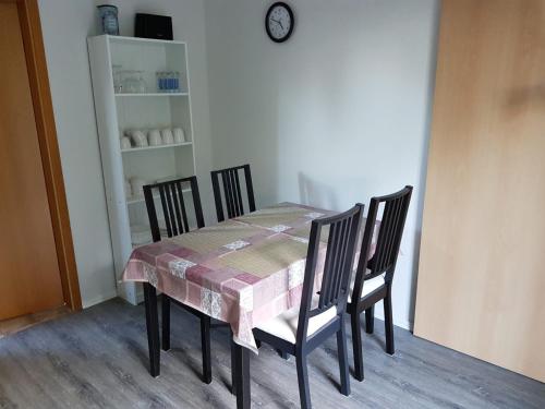 a dining room table with four chairs and a clock at NEU Ferienwohnung Kropp OG - Rechts in Kropp