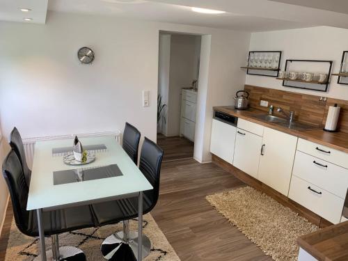 a kitchen with a white table and black chairs at NEU Ferienwohnung MONTE in Walsrode in Walsrode