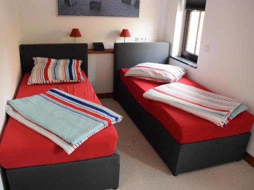 2 łóżka w pokoju z czerwonymi i niebieskimi kocami w obiekcie NEU! Moderne FeWo Nähe Plauer See 
