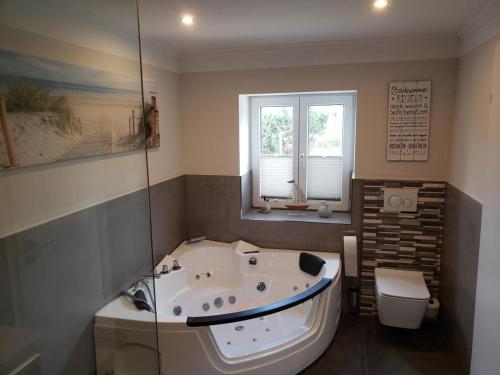 y baño grande con bañera y aseo. en Ferienhaus Kastanie mit Whirlpool Kamin und Sauna, en Blekendorf