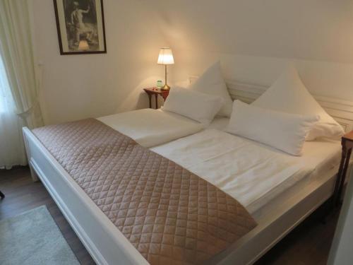 Bett mit weißer Bettwäsche und Kissen in einem Zimmer in der Unterkunft Schicke FeWo Johanna an der Nordsee Dachterrasse in Lütetsburg