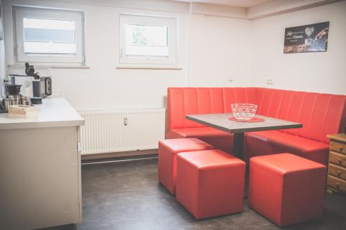 uma cozinha com uma mesa e duas cadeiras vermelhas em NEU! Moderne Ferienwohnung Knüllwald em Knüllwald