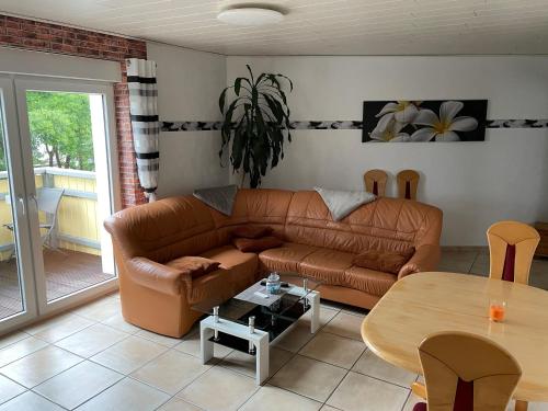 a living room with a brown leather couch and a table at NEU! Ferienwohnung am Bauna in Baunatal