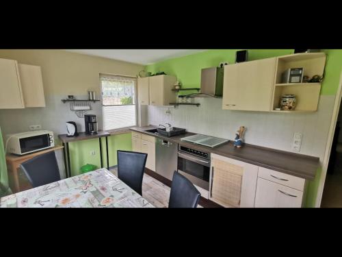 una cucina con pareti verdi e tavolo con sedie di NEU! Ferienwohnung am Schwedenberg a Elfershausen