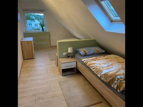 1 dormitorio en el ático con cama y ventana en NEU! Ferienhaus am Moor, en Wiesmoor