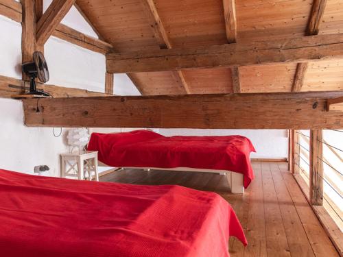 Duas camas com lençóis vermelhos num quarto com tectos em madeira em NEU! Studio Beim Kirchschuster em Schernfeld