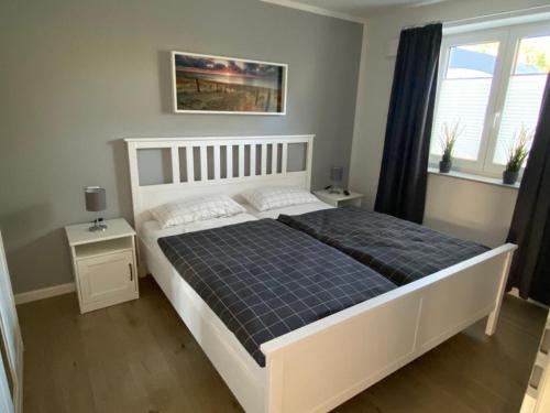 a bedroom with a large white bed with a blue blanket at NEU! Moderne Ferienwohnung Almdorf in Almdorf