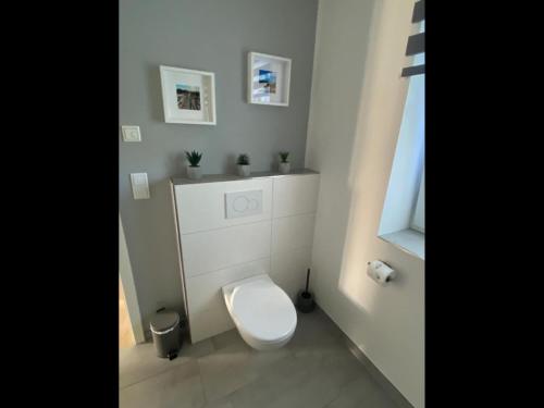 a white bathroom with a toilet and a window at NEU! Moderne Ferienwohnung Almdorf in Almdorf
