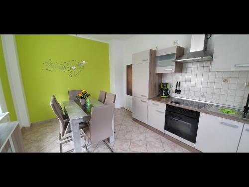 una cocina con mesa, sillas y una pared verde en NEU! Ferienwohnung Unger, en Schwarzenberg