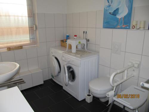 y baño con lavadora y aseo. en Ferienhaus Fahrrinne 12, en Dornum