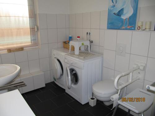 a bathroom with a washing machine and a toilet at Ferienhaus Fahrrinne 12 in Dornum