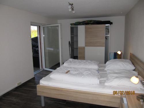 1 cama con sábanas blancas y almohadas en una habitación en Ferienhaus Fahrrinne 12, en Dornum