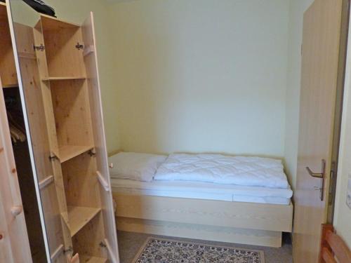 Habitación pequeña con cama y estanterías en Fehaus Spiekeroog Wohnung 6, en Dornumersiel