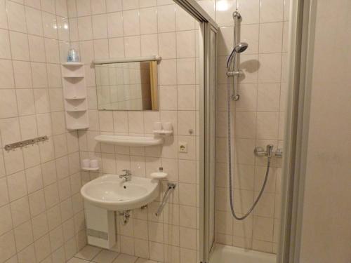 y baño blanco con lavabo y ducha. en Fehaus Spiekeroog Wohnung 6, en Dornumersiel