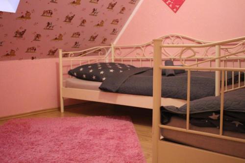 um quarto com 2 beliches e uma parede rosa em Ferienwohnung Geeske im Gulfhof em Krummhörn