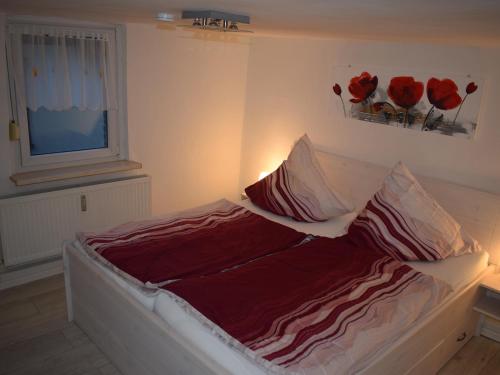a bedroom with a bed with red sheets and a window at Ferienwohnung Völkel in Tangermünde
