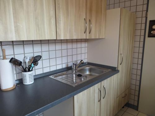 a kitchen counter with a sink and wooden cabinets at Ferienwohnung Hafenkoje in Dornum