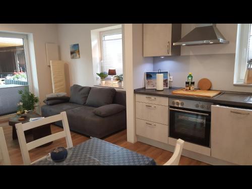 a kitchen and a living room with a couch at NEU! Ferienwohnung Amrum in Taarstedt
