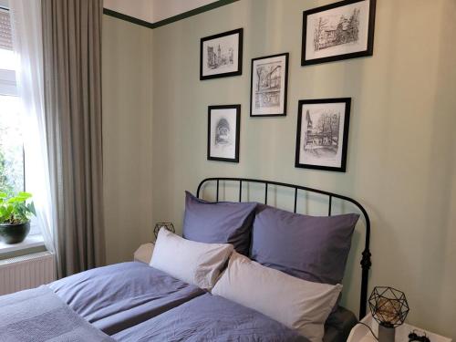 - un lit dans une chambre avec des photos sur le mur dans l'établissement NEU! Stilvolle FeWo Finsterwalde, à Finsterwalde