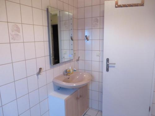 y baño con lavabo y espejo. en Ferienhaus Meerzeit, en Nessmersiel