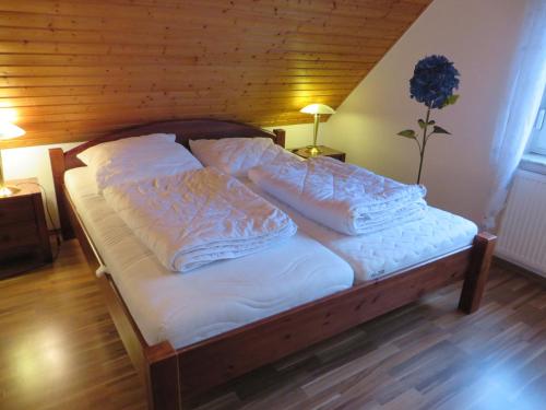 Una cama con sábanas blancas y almohadas. en Ferienhaus Meerzeit, en Nessmersiel