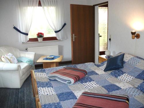 a bedroom with a bed and a couch and a window at NEU! Nordsee-Ferienhaus Lukas in Dornum