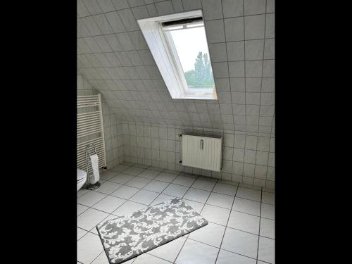 a bathroom with a white tiled floor and a window at NEU! FeWo Gremminer See in Gräfenhainichen