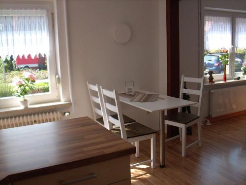 a dining room with a table and chairs and two windows at NEU! Ferienwohnung Kruse EG in Norden