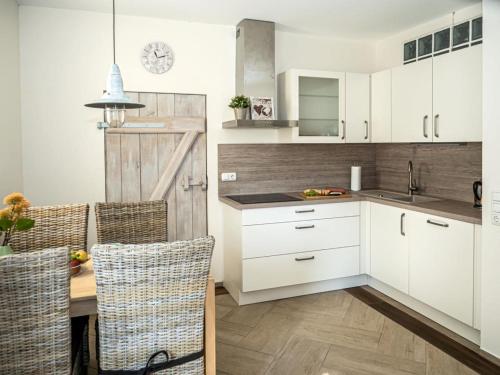 a kitchen with white cabinets and a table with chairs at Ferienwohnung Meer und Muh in Strenglin