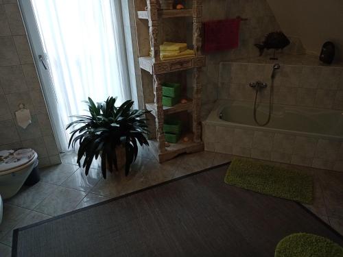 a bathroom with a plant next to a bath tub at NEU Ferienhaus mit Poolhalle und Sauna in Pyrbaum