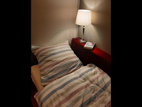 a bed with a pillow and a lamp on a table at NEU! Schicke Ferienwohnung Niebüll in Niebüll