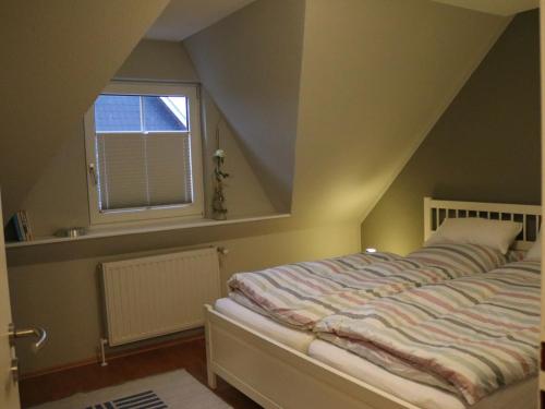 1 dormitorio con cama y ventana en NEU! Schicke Ferienwohnung Niebüll, en Niebüll