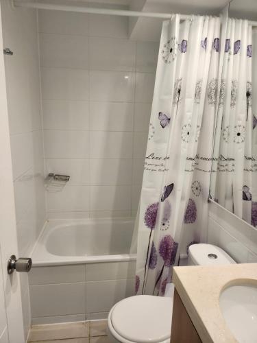 a bathroom with a tub and a toilet and a shower curtain at Quebrada de la Candelaria II in Algarrobo
