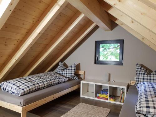 a attic bedroom with two beds and a window at NEU! Modernes Ferienhaus Hohensayn in Lautzenbrücken