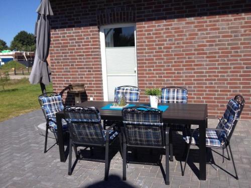 a wooden table with chairs and an umbrella on a patio at NEU! Modernes Ferienhaus Strandgut in Garrel