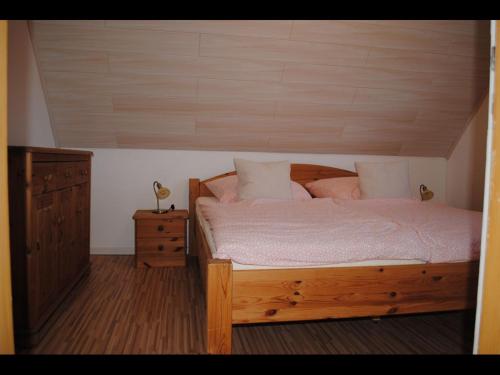ein Schlafzimmer mit einem Holzbett und einer Holzkommode in der Unterkunft NEU! Ferienhaus NordseeGlück in Dornum