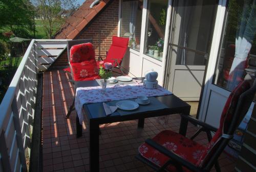 a patio with a table and chairs on a balcony at NEU! Schönes Urlaubsdomizil an der Nordsee in Stedesdorf